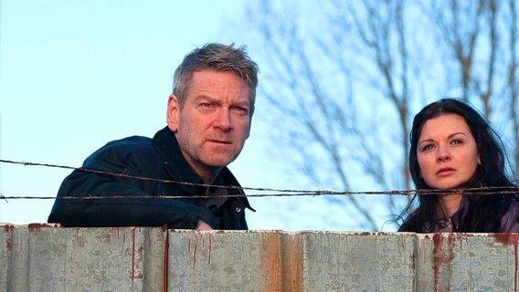 Kurt Wallander (gespielt von Kenneth Branagh) schaut mit seiner Kollegin Anne-Britt Hoglund (Sarah Smart) über einen Vorsprung. © HR/Degeto/Yellow Bird Rights/Left Bank Pictures 