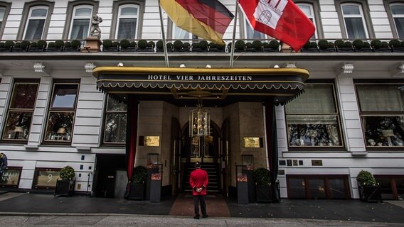 Haupteingang des Fairmont Hotel Vier Jahreszeiten in Hamburg. Davor steht ein Concierge im roten Sakko. © picture alliance / Eibner-Pressefoto | Eibner-Pressefoto 