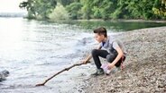 Neles Sohn Niklas (Noah Calvin) fischt Geldscheine aus dem Bodensee. © NDR/ARD/SWR/Patrick Pfeiffer 
