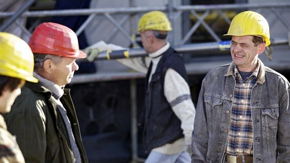 Auf der Baustelle herrscht angespannte Stimmung. Bauleiter Volker Angermann (Ronald Nitschke, 2.v.li.) ärgert sich darüber, dass eine falsche Lieferung angekommen ist und die Liefereinfahrt nicht frei ist. Sein Vorarbeiter und langjähriger Freund Mario Goepfert (Henning Peker, re.) soll das Auto wegfahren obwohl er über Sehbeschwerden klagt. Volker kann Mario, der ständig über irgendwelche gesundheitlichen Beschwerden klagt, nicht mehr ernst nehmen. © NDR/MDR/Wernicke 