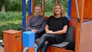 Bettina Tietjen mit Schauspieler Hinnerk Schönemann bei einer Floßfahrt auf der Müritz-Elde-Wasserstraße. © NDR/beckground tv/Marvin Vehring 
