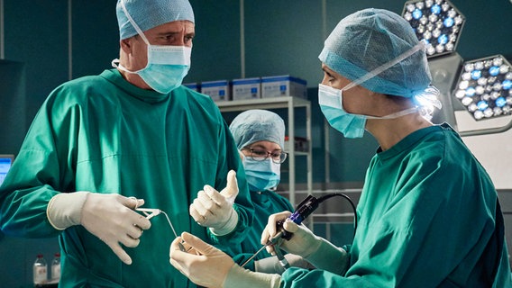 Der renommierte Schweizer Neurochirurg Dario Brosi (Markus Böker, li.) kommt an die Sachsenklinik, um zu demonstrieren, wie man eine Hypophysen-OP schneller und effektiver durchführt. Als Assistenz an seiner Seite, steht Dr. Lea Peters (Anja Nejarri, re.), seine ehemals beste Studentin an der Uni in Zürich. Brosi erweist sich bei der OP als genauso gut, wie sein Ruf, bis ihn ein Krampf in der Hand dazu zwingt die OP an Lea abzugeben. Der renommierte Schweizer Neurochirurg Dario Brosi (Markus Böker, li.) kommt an die Sachsenklinik, um zu demonstrieren, wie man eine Hypophysen-OP schneller und effektiver durchführt. Als Assistenz an seiner Seite, steht Dr. Lea Peters (Anja Nejarri, re.), seine ehemals beste Studentin an der Uni in Zürich. Brosi erweist sich bei der OP als genauso gut, wie sein Ruf, bis ihn ein Krampf in der Hand dazu zwingt die OP an Lea abzugeben. © NDR/MDR/Saxonia/Wernicke