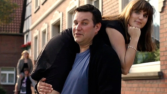 Ein Mann trägt eine über die Schulter gelegte Frau  