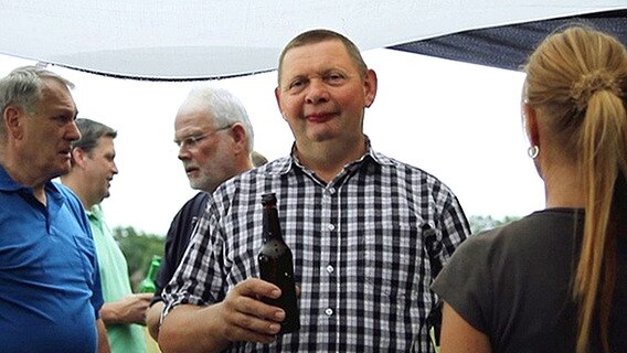 Ein Mann mit einer Bierflasche in der Hand bei einer Party  