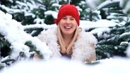 Eine Frau steht zwischen schneebedeckten Tannen  