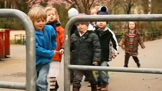 Mehere Kinder gehen an einem Geländer vorbei  