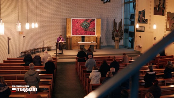 Ein Pfarrer steht vor einer Kirchengemeinde in einer Kirche © NDR 