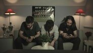 Drei niedergeschlagene Männer auf einem Sofa  