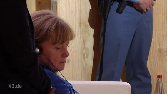 Angela Merkel mit Kopfhörern.  