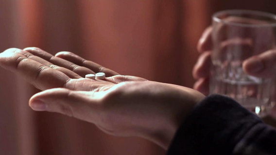 Eine Hand mit zwei kleinen Tabletten. © NDR/Kulturjournal 