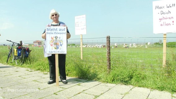 Demonstrantin vor eingezäuntem Strand  