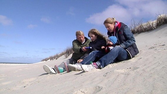 Familie Zimmermann sitzt im Sand in den Dünen  