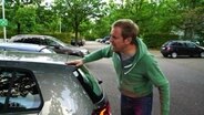 Ein Mann motzt ein Auto an.  