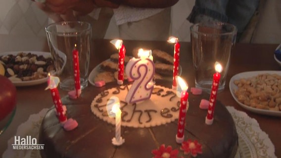 Eine Geburtstagstorte mit einer Kerze in Form einer 2.  