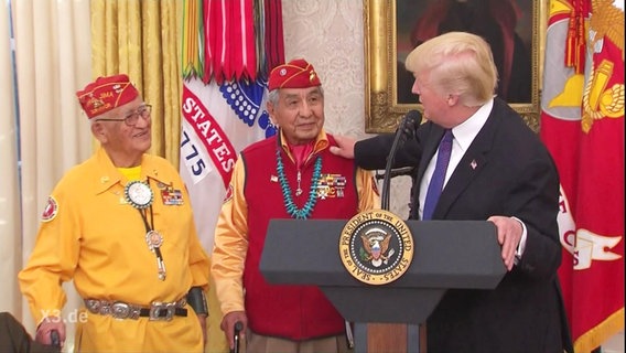 Donald Trump spricht mit zwei Vertretern der Ureinwohner Amerikas.  