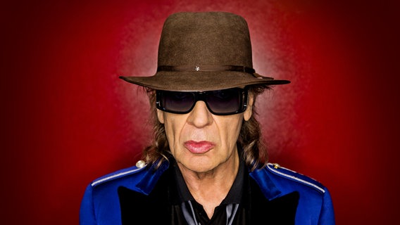Udo Lindenberg steht vor einer roten Wand und blickt in die Kamera. © Warner Music/Tine Acke Foto: Tine Acke