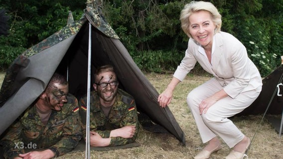 Ursuala von der Leyen steht neben einem Zelt in dem zwei Soldaten liegen  