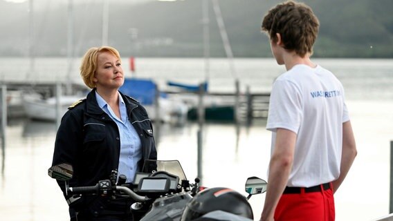 Nele Fehrenbach (Floriane Daniel, l.) befragt Leon Berg (Florian Burgkart, r.). Der Kollege des Toten soll erklären, wie er sich mit seinem Einkommen, ein solch teures Motorrad leisten kann? © ARD/Laurent Trümper 