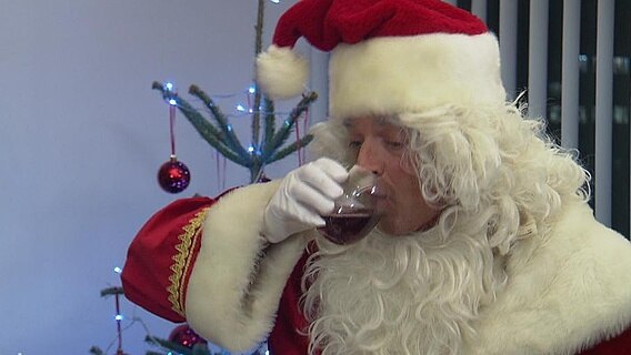 Ein Weihnachtsmann trinkt Wein  