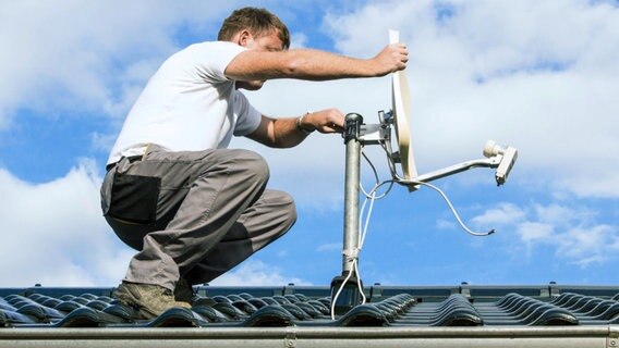 Monteur installiert eine Satellitenschüssel auf einem Dach. © Artalis/fotolia Foto: Artalis