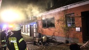 Feuerwehrleute stehen nach dem Einsatz vor einem Haus in Plau am See. © NDR Foto: Bölsche