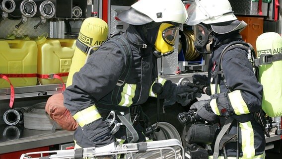 Feuerwehrmänner im Einsatz am Feuerwehrwagen. © Colourbox 