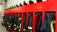 Kleiderspinde in einer Feuerwehrwache mit Uniformen und Helmen. © colourbox 