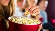 Eine Frau isst im Kino Popcorn. © fotolia Foto: Kzenon