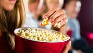 Eine Frau isst im Kino Popcorn. © fotolia Foto: Kzenon