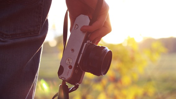 Nahaufnahme eines Fotoapparats, den ein Mann in der Hand hält. © Pixabay 