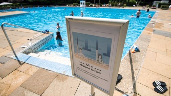 Ein Schild mit der Aufschrift "1,5 m Abstand halten" steht im Freibad Marienhöhe in Hamburg am Beckenrand. Ein Schild mit der Aufschrift "1,5 m Abstand halten" steht im Freibad Marienhöhe in Hamburg am Beckenrand. © Daniel Bockwoldt/dpa Foto: Daniel Bockwoldt