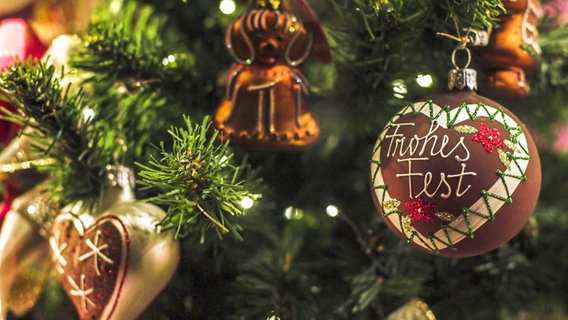 Verschiedene Weihnachtskugeln hängen an einer Kunsttanne. Auf einer braunen Kugel steht "Frohes Fest". © picture alliance/Presse-Bild-Poss Foto: Uta Poss