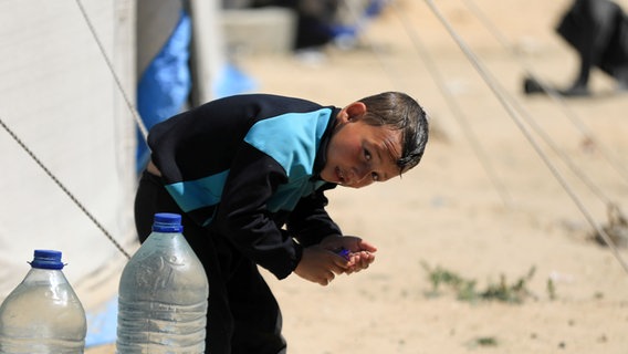 Ein Junge kühlt sich in Gaza mit Wasser ab © picture alliance / Anadolu | Yasser Qudaih Foto: Yasser Qudaih