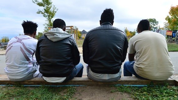 Vier junge Männer aus Eritrea sitzen in Saalfeld (Thüringen) vor einer Flüchtlingsunterkunft. © picture alliance/dpa Foto: Martin Schutt