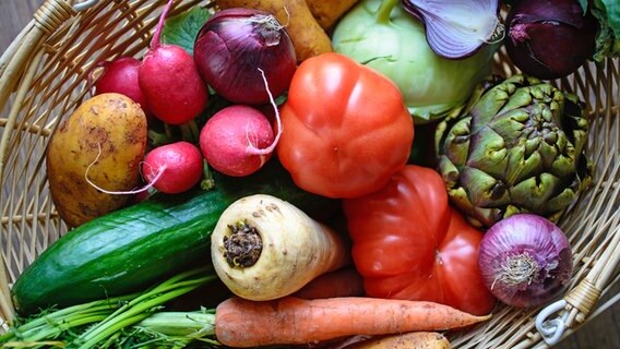 In einem Korb liegen frische Zwiebeln, Radieschen, Tomaten, Artischoken, Salatgurken und Kohlrabi. © Fotolia Foto: Visions-AD