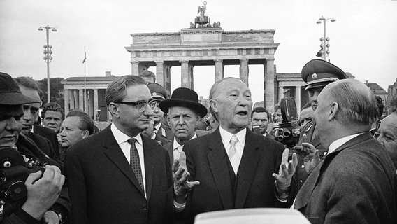 Bundeskanzler Konrad Adenauer (M) am 22. August 1961 mit Ernst Lemmer (l), Bundesminister für gesamtdeutsche Fragen, vor dem Brandenburger Tor in Berlin. © picture alliance / ASSOCIATED PRESS 