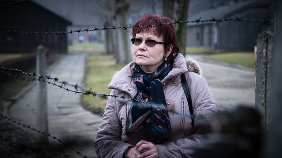 Die Fremdenführer Halina Świderska blickt auf einen Stacheldrahtzaun im ehemaligen KZ Auschwitz-Birkenau © NDR.de Foto: Christian Spielmann