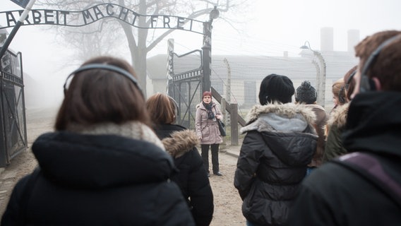 Auschwitz-Guide Halina Swiderska bei einer Führung unter dem Tor mit der Aufschrift "Arbeit macht frei" © NDR Foto: Christian Spielmann