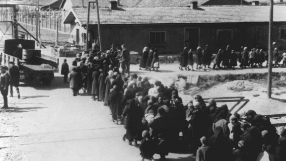 Ein Gruppe Häftlinge bewegt sich nach der Selektion zum Krematorium im KZ Auschwitz. Die Menschen hatten zuvor nach ihrer Ankunft im KZ auf der Todesrampe nach Geschlechtern getrennt Aufstellung nehmen müssen. Dann folgte die Selektion. (Undatierte Aufnahme). © dpa - Bildarchiv 