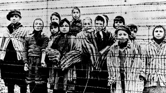 Kinder in Häftlingskleidung hinter einem Stacheldrahtzaun nach der Befreiung des KZ Auschwitz 1945. ©  picture alliance / AP Photo 