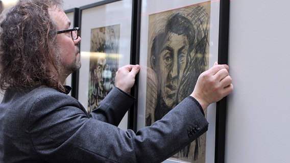 Der Kurator Jürgen Kaumkötter hängt ein Bild in der Ausstellung "Der Tod hat nicht das letzte Wort" auf. © NDR Foto: Judith Pape