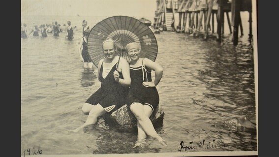 Zwei Frauen in Badekostümen mit einem Sonnenschirm 1926 an der Ostsee. © Jürgen Kraft 