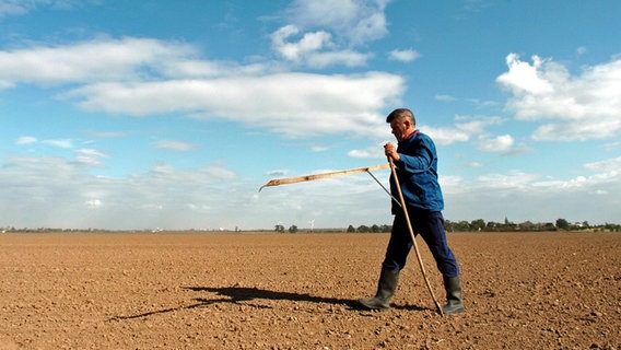 Ein Bauer misst mit einem Feldmesszirkel seinen Acker aus. © picture-alliance / ZB Foto: Peter Endig