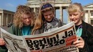 Jugendliche am Brandenburger Tor informieren sich am 21. Juni 1991 über das Ergebnis der Abstimmung über den neuen Regierungssitz nach der deutschen Wiedervereinigung. © picture-alliance / dpa Foto: Andreas Altwein
