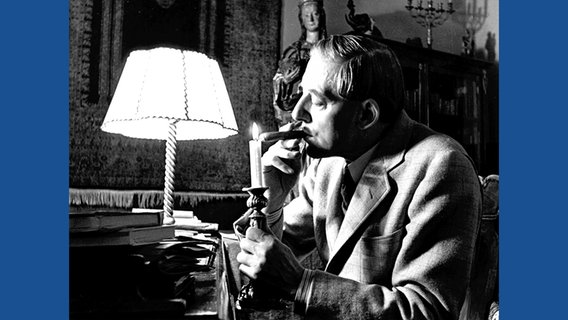 Waldemar Bonsels sitzt am Schreibtisch und entzündet eine Zigarre an einer Kerze © Waldemar Bonsels Stiftung 