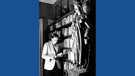 Waldemar Bonsels steht mit einem Buch in der Hand vor einem Bücherregal © Waldemar Bonsels Stiftung 
