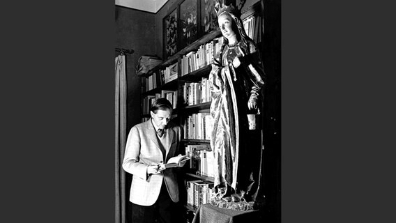 Waldemar Bonsels steht mit einem Buch in der Hand vor einem Bücherregal © Waldemar Bonsels Stiftung 