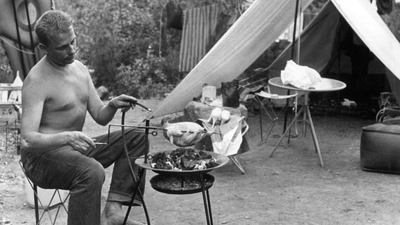 Ein Camper sitzt im Juli 1957 vor seinem Zelt und grillt ein Brathähnchen. © picture alliance/dpa Foto: Herbert Bögel