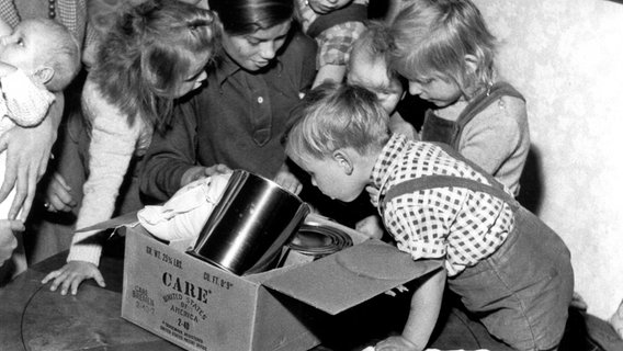 Kinder blicken neugierig in ein CARE-Paket. © CARE/www.care.de 