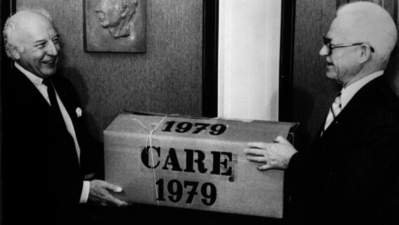 Bei seiner Verabschiedung 1979 nimmt Bundespräsident Walter Scheel ein CARE-Paket entgegen. © CARE/www.care.de 